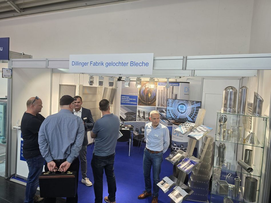 Messestand der Dillinger Fabrik gelochter Bleche auf der IFAT: Mehrere Besucher im Gespräch vor einer Präsentationsfläche mit verschiedenen Mustern und Bauteilen aus gelochten Blechen.